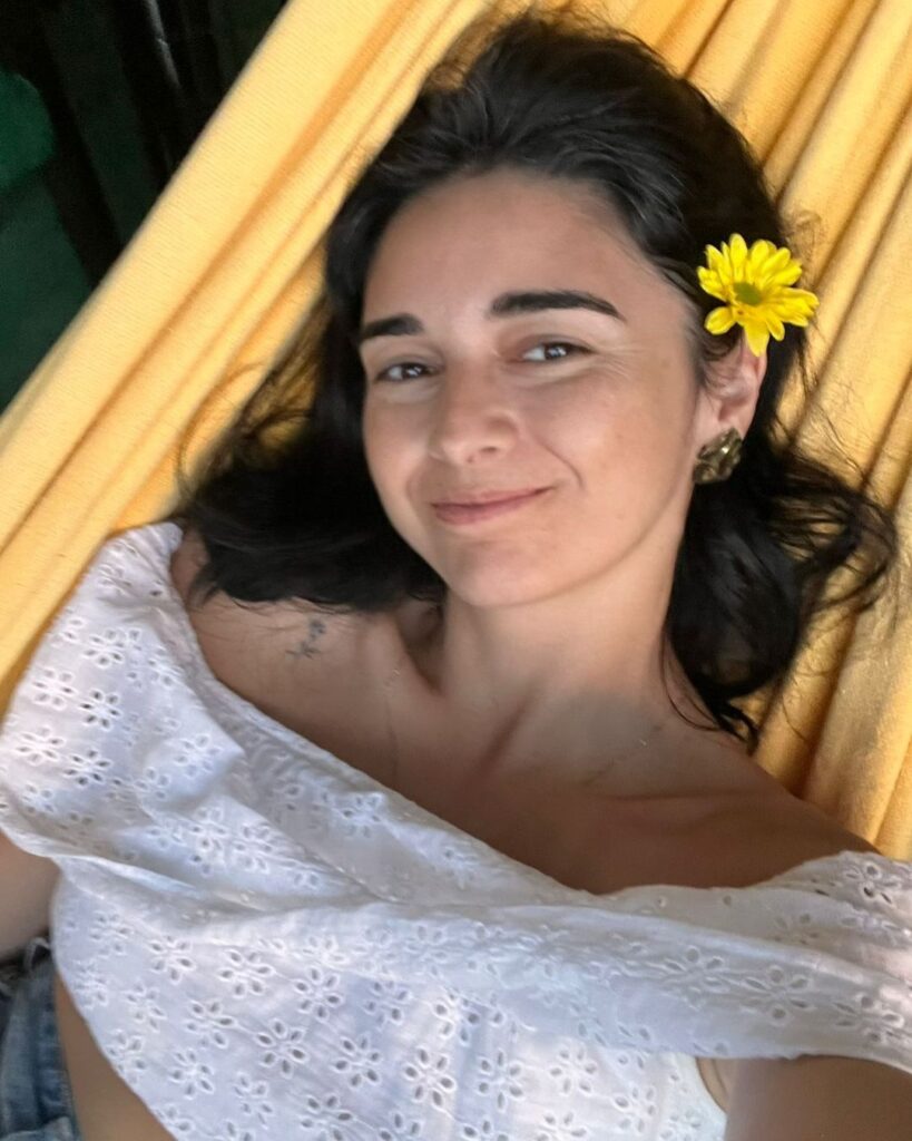 Leve sorriso na rede amarela, com flor amarela no cabelo preto sobre a orelha